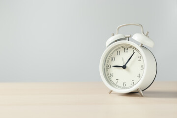 white retro alarm clock on wooden table.