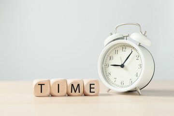 Text "Time" on wooden blocks cube with alarm clock.