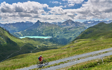 Fototapeta premium nice active senior woman riding her electric mountain bike in the silvretta mountain range above barrier lake Kopssee,near Gaschurn, Tyrol, Austria