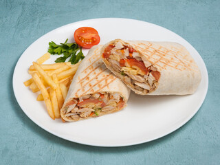shawarma with chicken and vegetables and french fries on a blue background