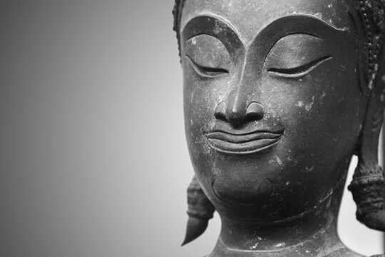 The head of an ancient Buddha statue was made of bronze. image on copy space gray background.