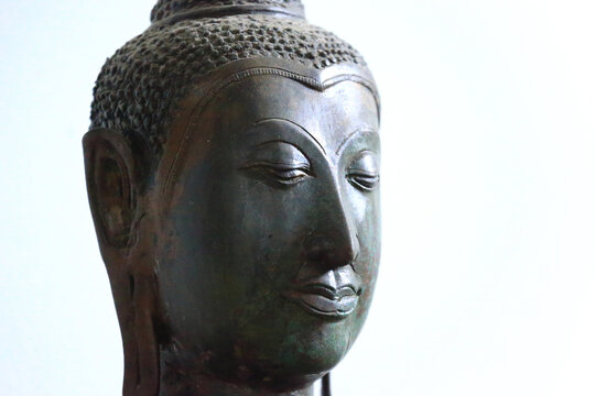 The head of an ancient Buddha statue was made of bronze. image on copy space white background.