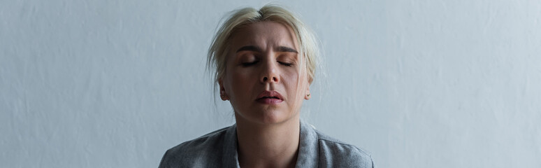 sad blonde woman with climax and closed eyes at home, banner.