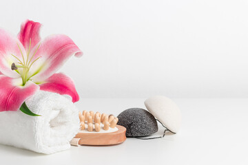 White towel with lily, wooden massager and konjac sponges. White background, spa concept, skincare