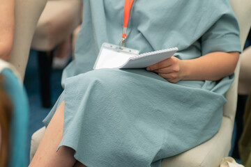 Woman in a mint-colored dress on her knee holds a notebook for notes at a conference, seminar. Concept of training, education, professional development