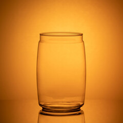 a glass heat-resistant jar on an orange background on a mirrored table