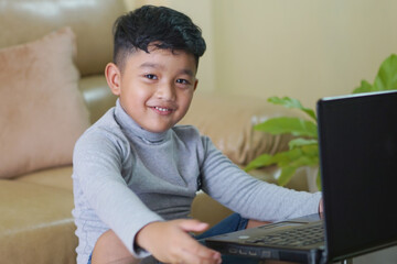 The Asian boy focusing working on laptop and have a cute smile