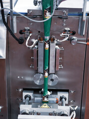 Ground coffee filling in sachet on vertical package filling machine. Food industry.