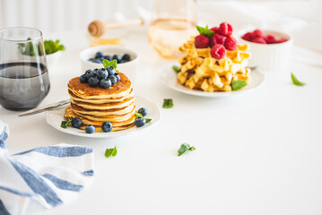 Summer breakfast. Homemade baked ricotta pancakes and Belgian waffles with fresh berries on white wooden table - obrazy, fototapety, plakaty