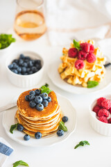 Summer breakfast. Homemade baked ricotta pancakes and Belgian waffles with fresh berries on white wooden table