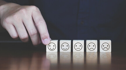 Concept of customer service, hand holding smile face icon on wood.