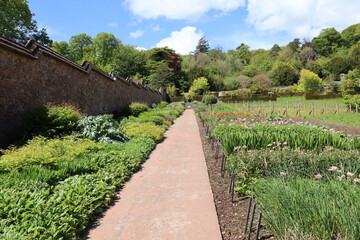 A gravel path runs alongside the unusual stepped effect of the wall of a kitchen garden at an...