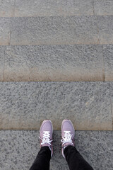 cropped image of female legs in shoes. Woman in pink sneakers descend stairs. First person view