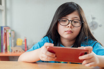 Cute Little Asian Girl Playing Game on Mobile Phone.