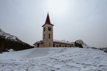 The white church, in the village of maloja, covered by snow during a late winter day, Switzerland - March 2022.