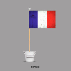 Grunge flag of France on a stick, in a small bucket. Isolated on a gray background. Signs and symbols. Flags.Design