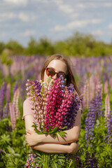 young woman in the field of flowers with bunch of lupines