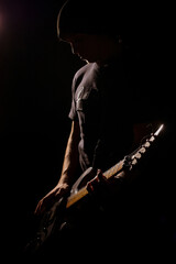 man playing on electric guitar in the dark