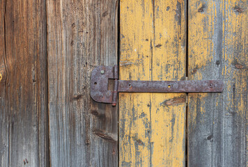 An old rusty hinge on an old wooden dilapidated door.