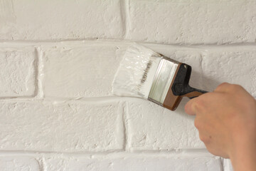 Painting a white brick wall in a fresh white color.