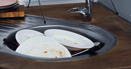 metallic sink full of dirty plates in kitchen. © LIGHTFIELD STUDIOS