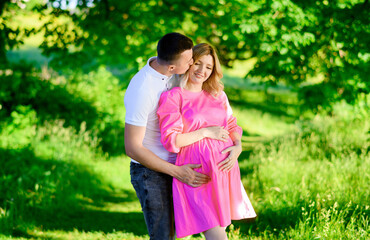 Naklejka premium Beautiful young couple of a man and a pregnant woman in the forest at sunset