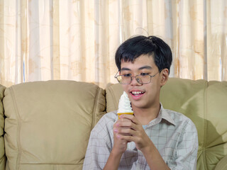 Asia boy kid hold vanilla ice cream in waffles cone happy smiling and eating deliciously in summer with have fun and good mood.
