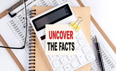 UNCOVER THE FACTS word on sticky with clipboard and notebook, business concept