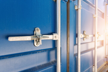 Close-up detail view of big blue metal freight cargo container door handle closed with padlock...