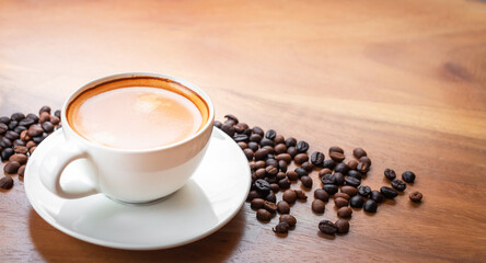Close-up of a cup of latte with golden foam and mixed or blend coffee beans  on an old wooden floor, top view.
