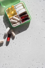Pill box with medicaments on light grey background, top view