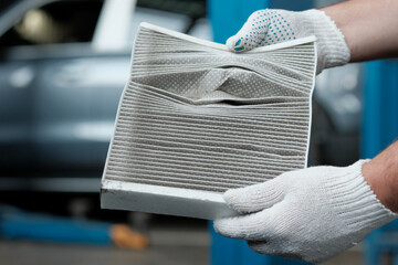 An auto mechanic holds a used air filter in his hands. Demonstration of the degree of contamination...