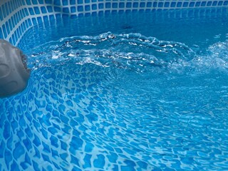 a rippling water fountain in a blue swimming pool