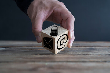 Businessman holds wooden blocks with contact us icon