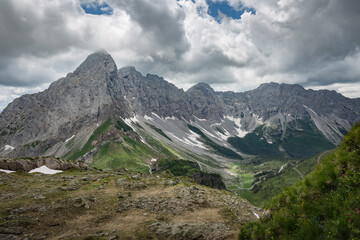 Fototapeta na wymiar Between Italy and Austria: mountain hiking Trail Road near Volaia Lake Raunchkofer Mountain (Lago di Volaia Monte). Grey sky before thunderstorm background.