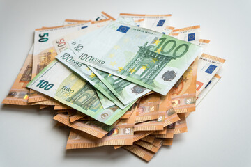 Batch of euro currency banknotes nominated 50 and 100 on a white background.