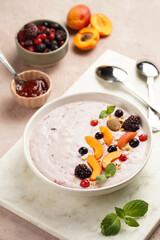 Traditional breakfast semolina porridge - purple creamy pudding with apricot slices, frozen berries, fresh mint, jelly on marble board
