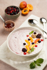 Traditional breakfast semolina porridge - purple creamy pudding with apricot slices, frozen berries, fresh mint, jelly on marble board
