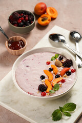 Traditional breakfast semolina porridge - purple creamy pudding with apricot slices, frozen berries, fresh mint, jelly on marble board