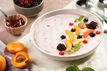 Traditional breakfast semolina porridge - purple creamy pudding with apricot slices, frozen berries, fresh mint, jelly on marble board