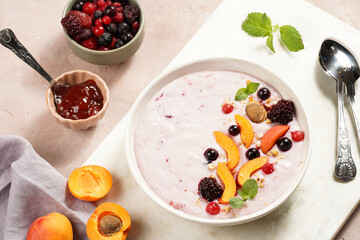 Traditional breakfast semolina porridge - purple creamy pudding with apricot slices, frozen berries, fresh mint, jelly on marble board