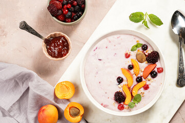 Traditional breakfast semolina porridge - purple creamy pudding with apricot slices, frozen berries, fresh mint, jelly on marble board