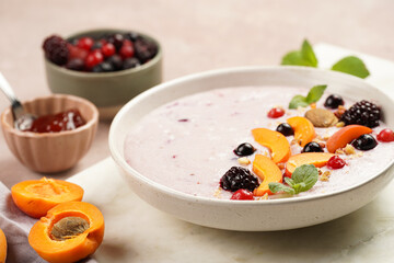 Traditional breakfast semolina porridge - purple creamy pudding with apricot slices, frozen berries, fresh mint, jelly on marble board