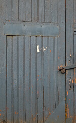 Old gray blue wooden door with the padlock from stables