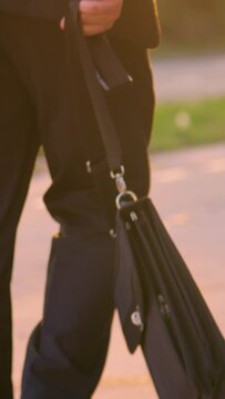 SLOW MOTION, CLOSE UP, LENS FLARE: Unrecognizable man in a black suit experiencing a nervous breakdown after a bad day at work. Sad young businessman walking home at sunset after losing his job.