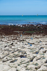 Low tide period and view on ocean bed and chalk cliffs of Porte d'Aval arch in Etretat, Normandy, France. Tourists destination.