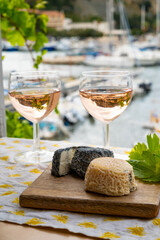 Rose wine in glasses served with goat cheeses on outdoor terrace with view on old fisherman's...