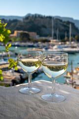 Two glasses of white wine from Cassis region served on outdoor terrace with view on old fisherman's harbour with colourful boats in Cassis, Provence, France