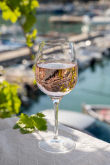 Rose wine in glass served on outdoor terrace with view on old fisherman's harbour with colourful boats in Cassis, Provence, France