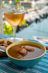 Homemade fish soup with croutons served with glass of cold rose wine and view on colorful...